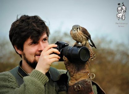 Man with bird sitting on his camera at The Falconry School